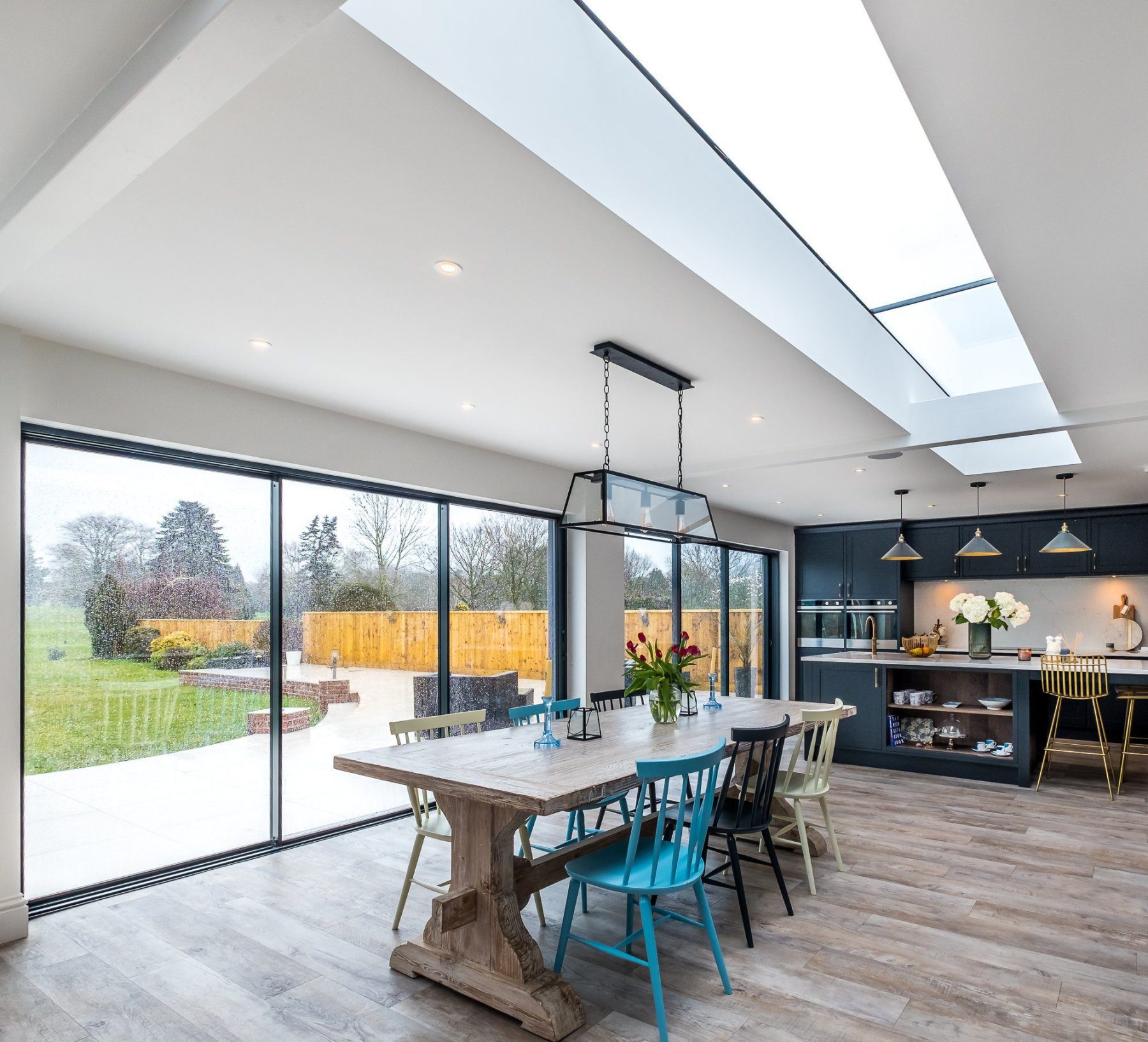 An internal view of the rear brick extension showing the open plan dining area with the kitchen in the background, and a large ribbon of skylight above, at Topsham Road.