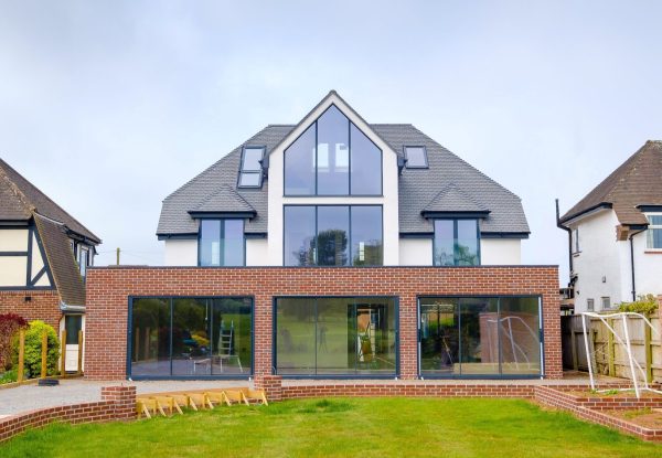 An external view of the brick rear extension with large glass sliding patio doors to a transformed 1930s detached family home on Topsham Road.