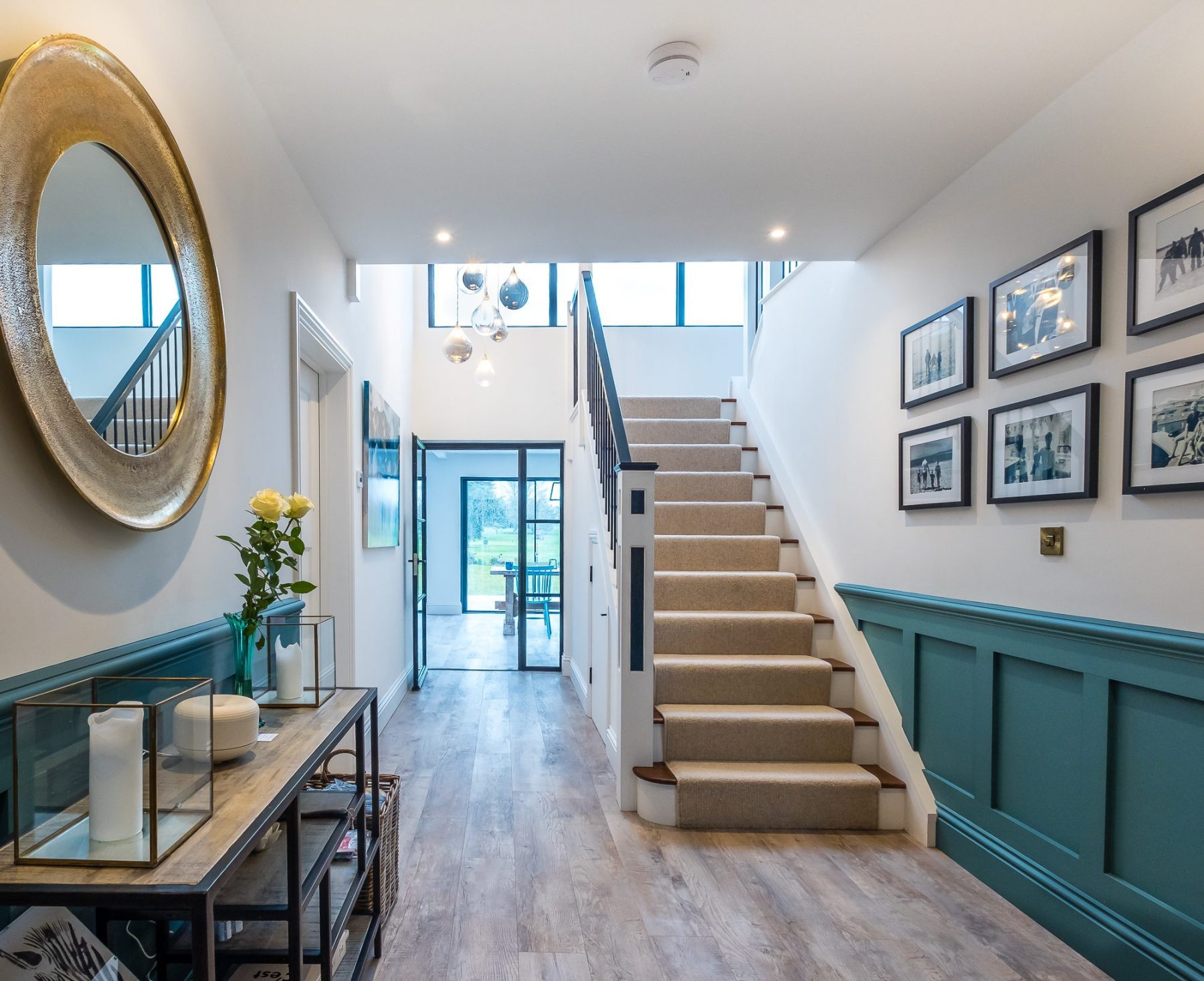 An internal view of the double height entrance hallway with the stairs to one side leading to the first floor galleried landing, and views through into the extension.