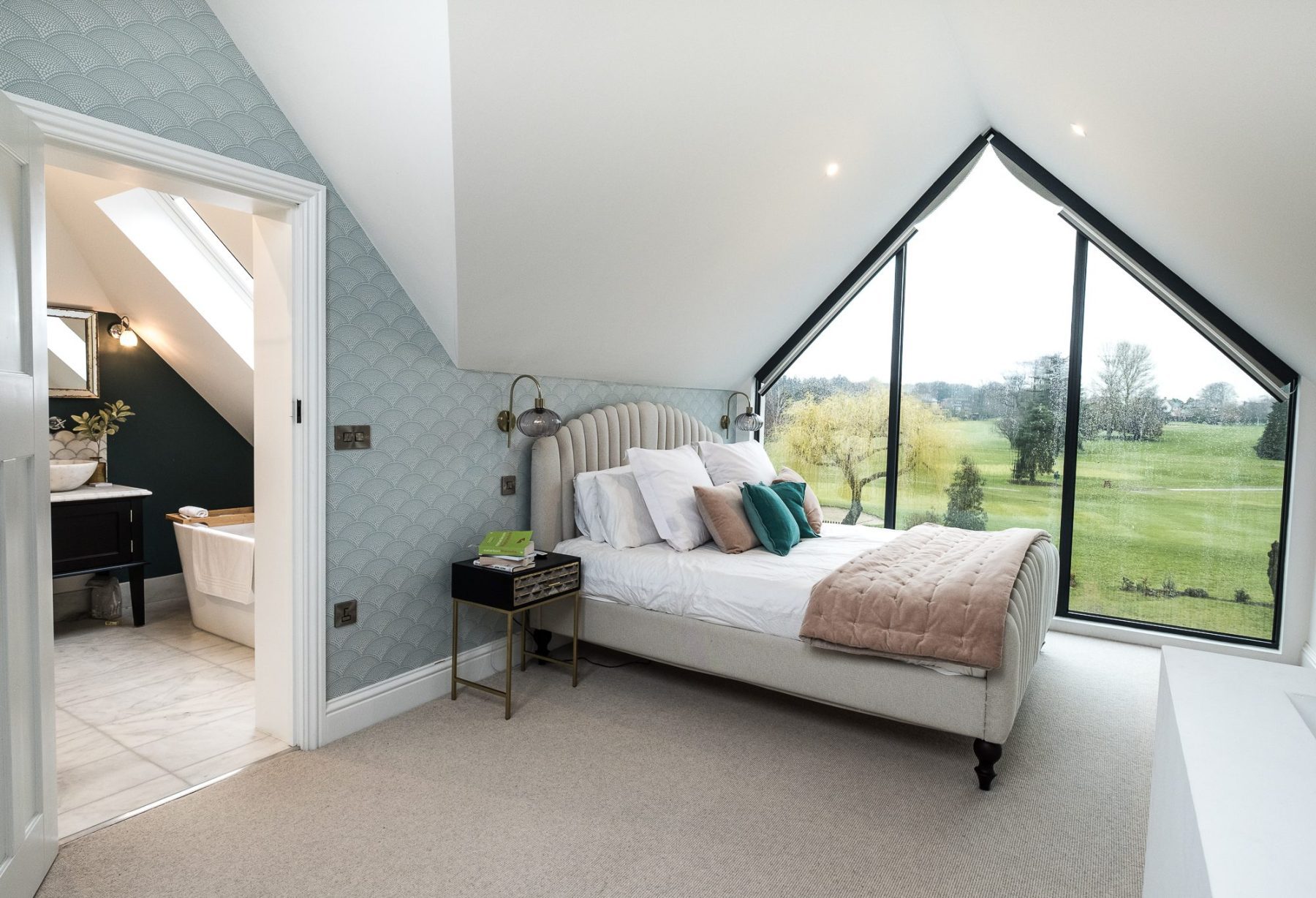 An internal view of the principal bedroom in the loft conversion at Topsham Road; with the large gable end feature window looking across Exeter Golf and Country Club and ensuite in the background.