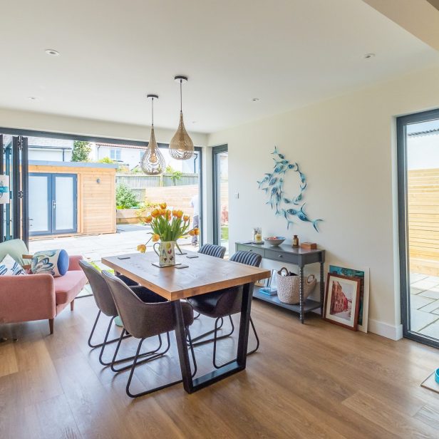 An internal view of the new light-filled dining area with the glass folding doors fully opened to the rear garden of the bungalow in Sidford Sidmouth.